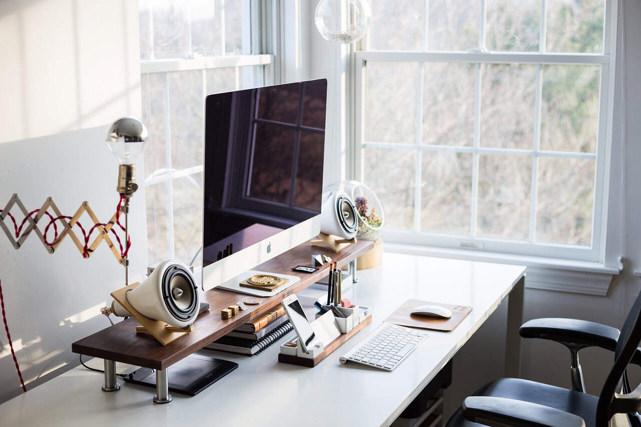 Modern home office desk with a computer, speakers, and workstation setup, representing a professional space where lawyers can record podcasts and create content.
